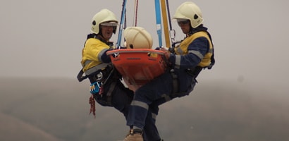 Two rescue workers and injured worker in a litter suspended from rescue device
