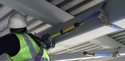 Worker among beams connected by pair of self-retracting lanyards

