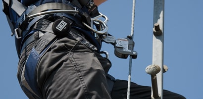 Worker climbing tower ladder connected to cable ladder safety system
